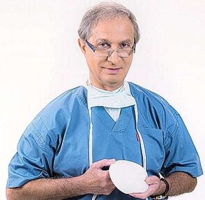 zdravnik drži implantat za povečanje prsi